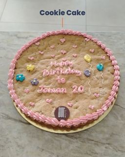 Giant cookie cake with pink frosting and balloons, by DOT Cake Art