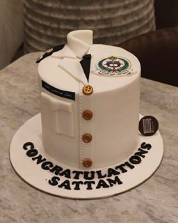 White cake shaped like a uniform with an emblem, by DOT Cake Art