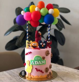Sesame Street cake with colorful balloon arch, by DOT Cake Art