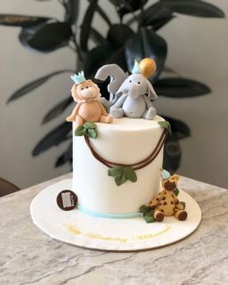White cake with baby safari animals, elephant and giraffe, by DOT Cake Art