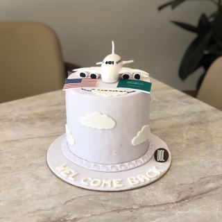 White cake with plane and flags, welcome back, by DOT Cake Art