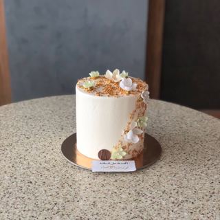 White cake with small flowers and gold dust, by DOT Cake Art