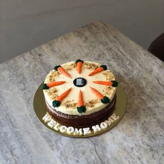 Carrot cake with carrot toppers and welcome home sign, by DOT Cake Art