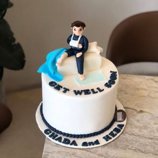 White cake with a patient figure and get-well message, by DOT Cake Art
