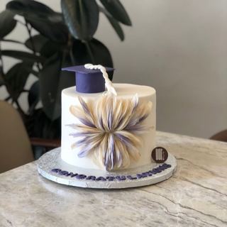 White cake with purple petals and grad cap, by DOT Cake Art