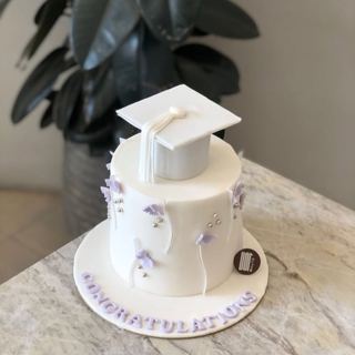 White cake with white graduation cap and flowers, by DOT Cake Art