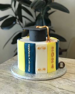 Yellow and navy book-stack cake with grad cap, by DOT Cake Art
