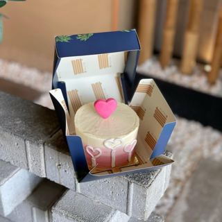 Small white cake with a pink heart topper, by DOT Cake Art
