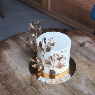 كيكة بيضاء بغصن أوراق برونزية وورق ذهب بعبارة Happy Eid من دوت كيك آرت