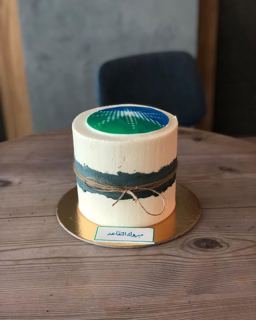 White cake with organisation logo and twine, by DOT Cake Art