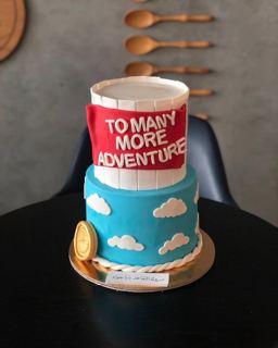 Two-tier blue cake with clouds and red flag, by DOT Cake Art