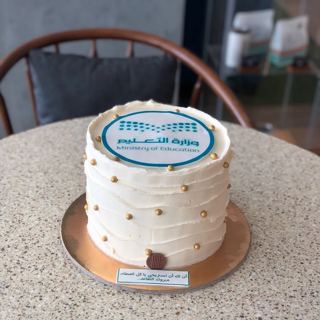 White cake with Ministry of Education logo, by DOT Cake Art