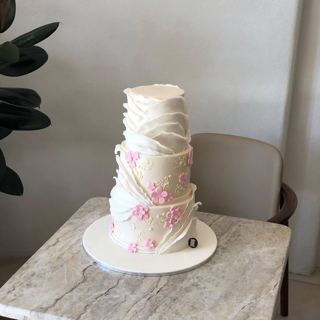 Two-tier white ruffled cake with pink flowers, by DOT Cake Art