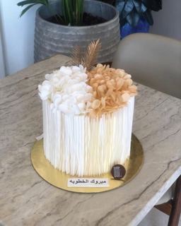 White textured cake topped with dried flowers, by DOT Cake Art