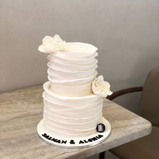 Two-tier white ruffled cake with flowers, by DOT Cake Art